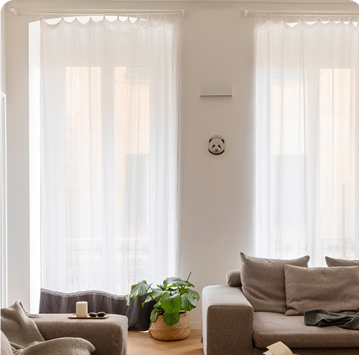 peaceful living room with big white curtains covering the windows